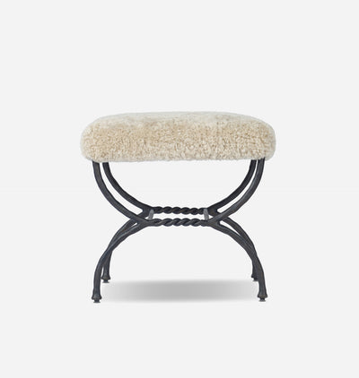 A small bench with a cream-colored shaggy sheepskin cushion on a black metal frame, shown against a plain light gray background.