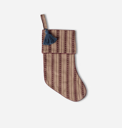 A patterned Christmas stocking with a brown and beige geometric design and a dark blue tassel, shown against a light gray background.