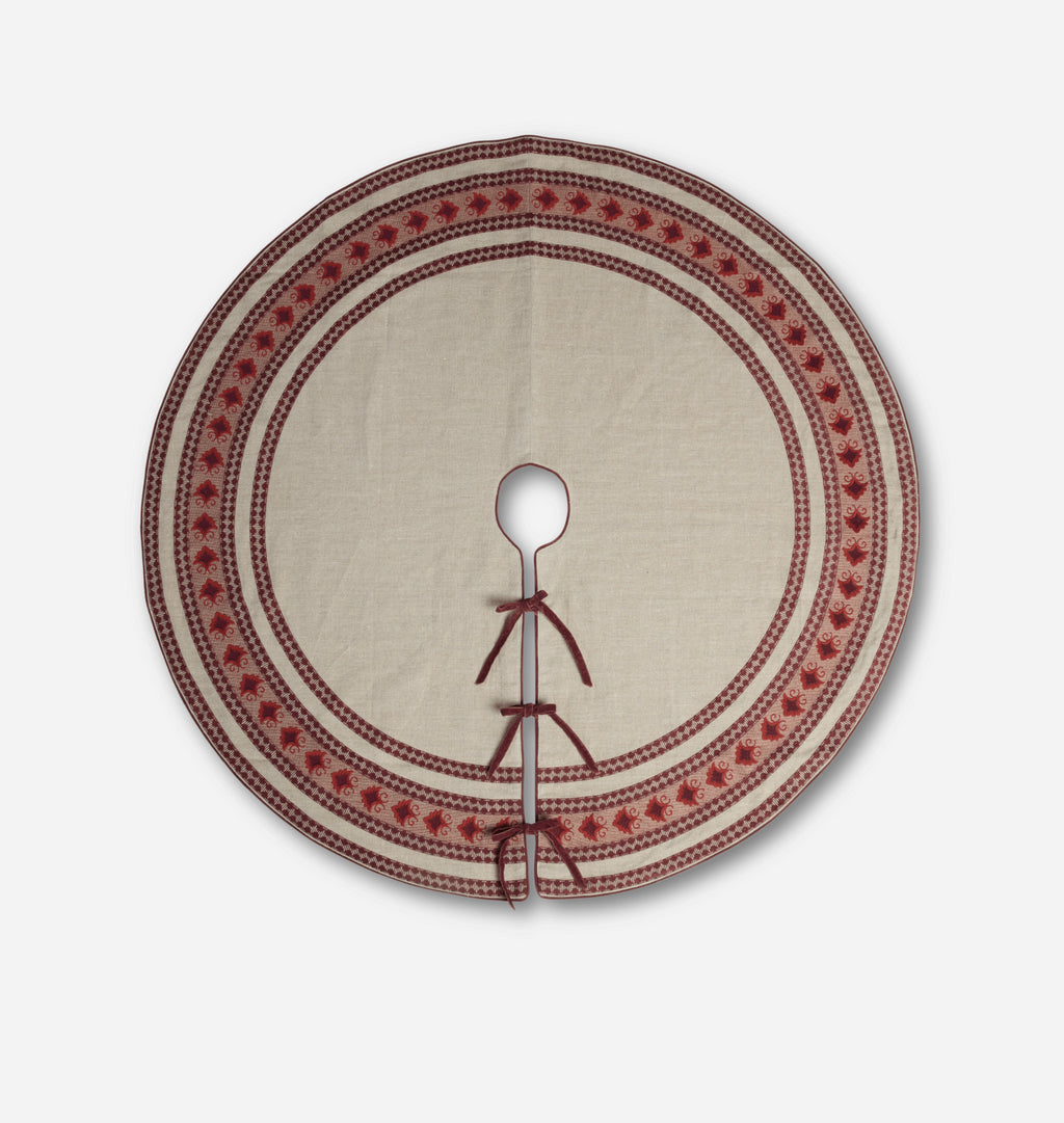 A round beige linen fabric tree skirt with a red embroidered border and a central hole for hanging, shown against a plain light gray background.