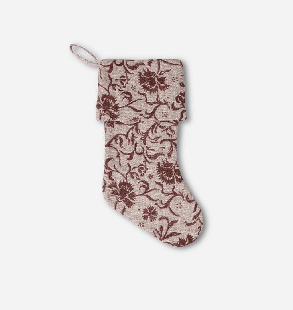 A fabric Christmas stocking with a brown floral and vine pattern on a light beige background, featuring a hanging loop at the top, shown against a plain light gray background.