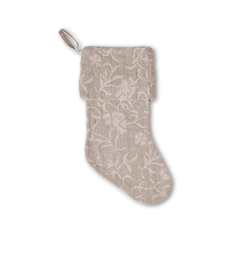 A beige fabric Christmas stocking with a white floral embroidered pattern and a hanging loop, shown against a plain white background.