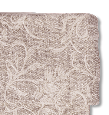 A close-up of an embroidered fabric with a floral damask pattern in a light taupe-beige color, shown against a plain white background.