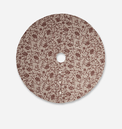 A round decorative tree skirt featuring an all-over floral vine pattern in dark brown on a warm beige background, shown against a light gray studio background.