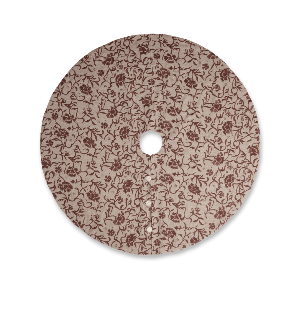A round beige tree skirt with a reddish brown embroidered floral and scroll motif pattern with three button closures set against a white background