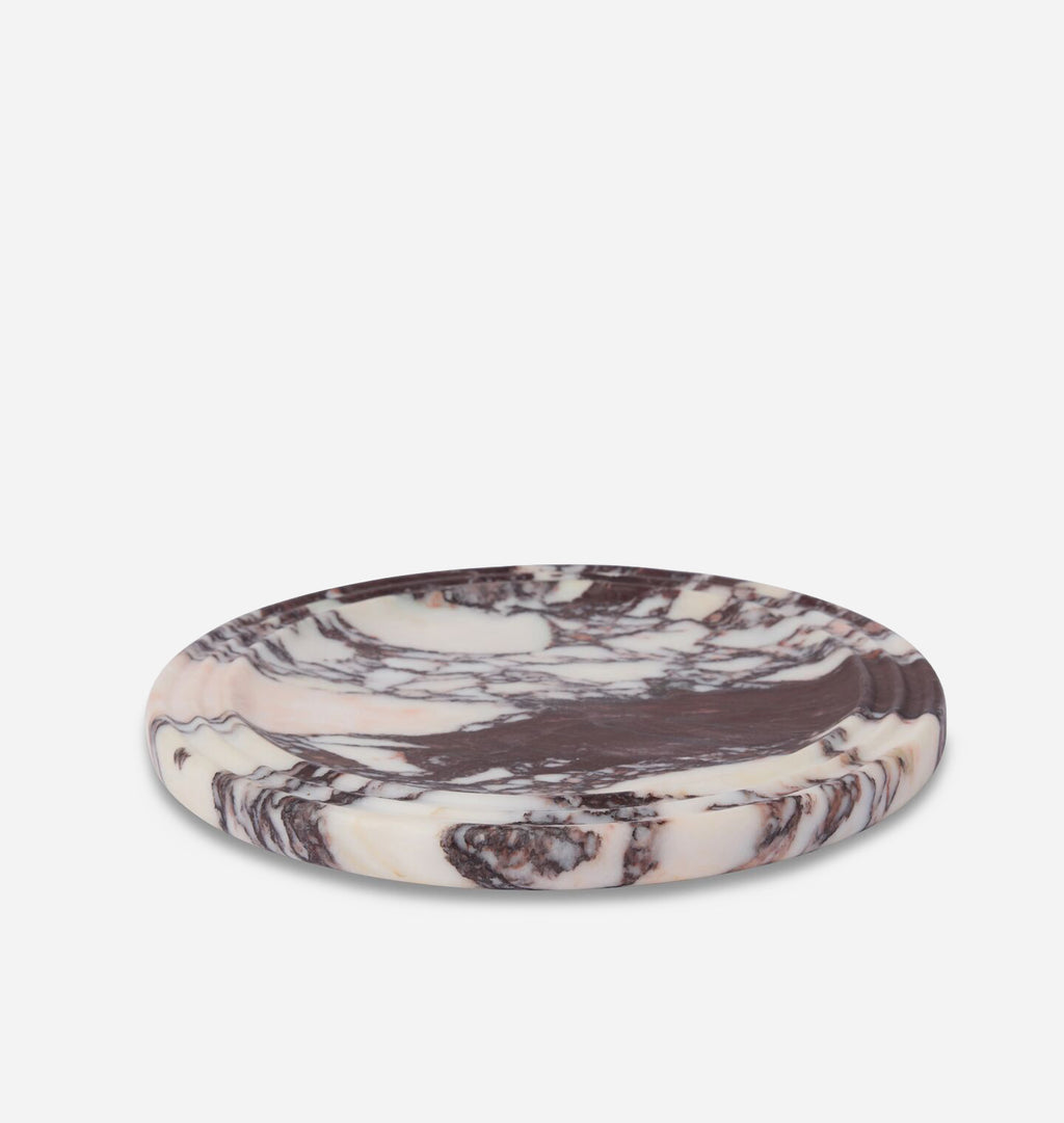 A round, shallow stone tray with a marbled pattern of cream, beige, and dark brown, photographed on a seamless white background.