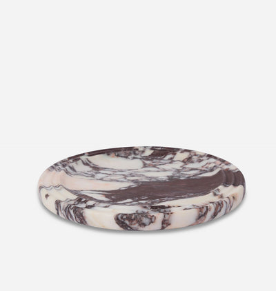 A round, shallow stone tray with a marbled pattern of cream, beige, and dark brown, photographed on a seamless white background.