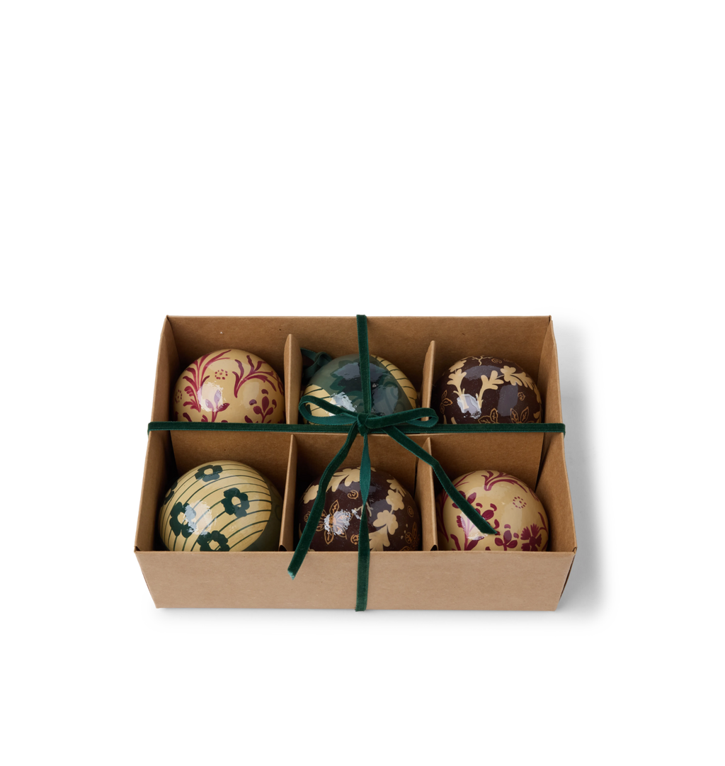 A set of decorative paper mache ornaments with floral patterns with green velvet ties in a gift box