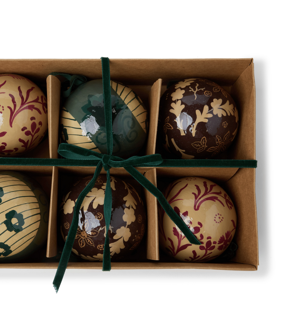 A set of decorative paper mache ornaments with floral patterns with green velvet ties in a gift box
