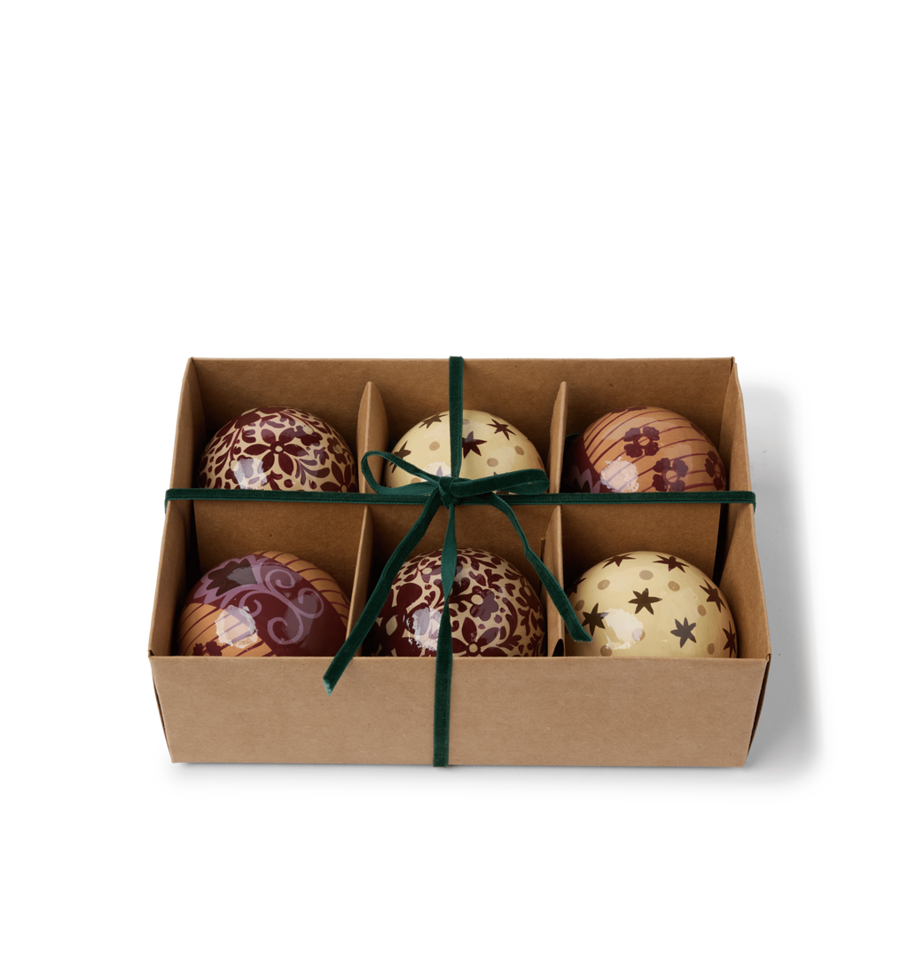 A set of decorative paper mache ornaments with star and floral patterns with green velvet ties in a gift box