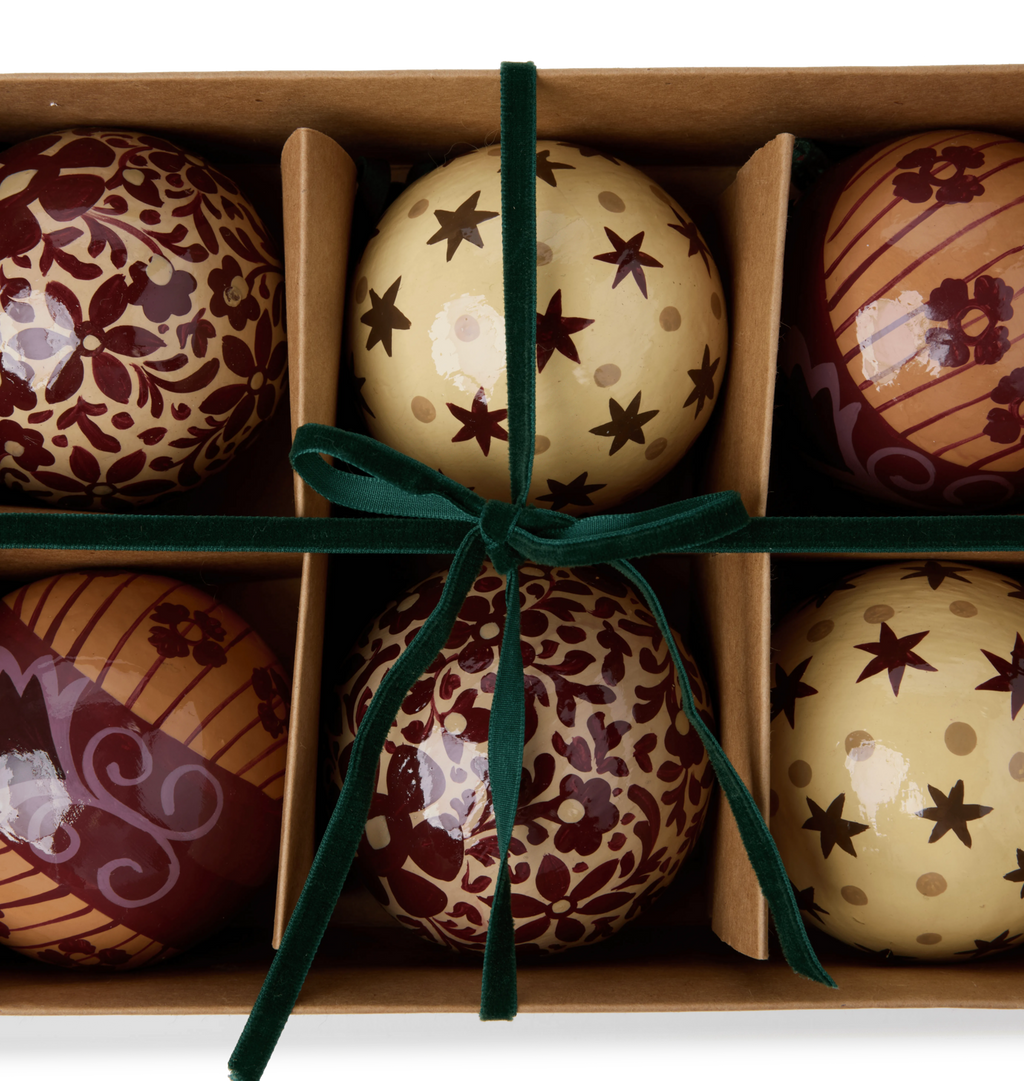 A set of decorative paper mache ornaments with star and floral patterns with green velvet ties in a gift box