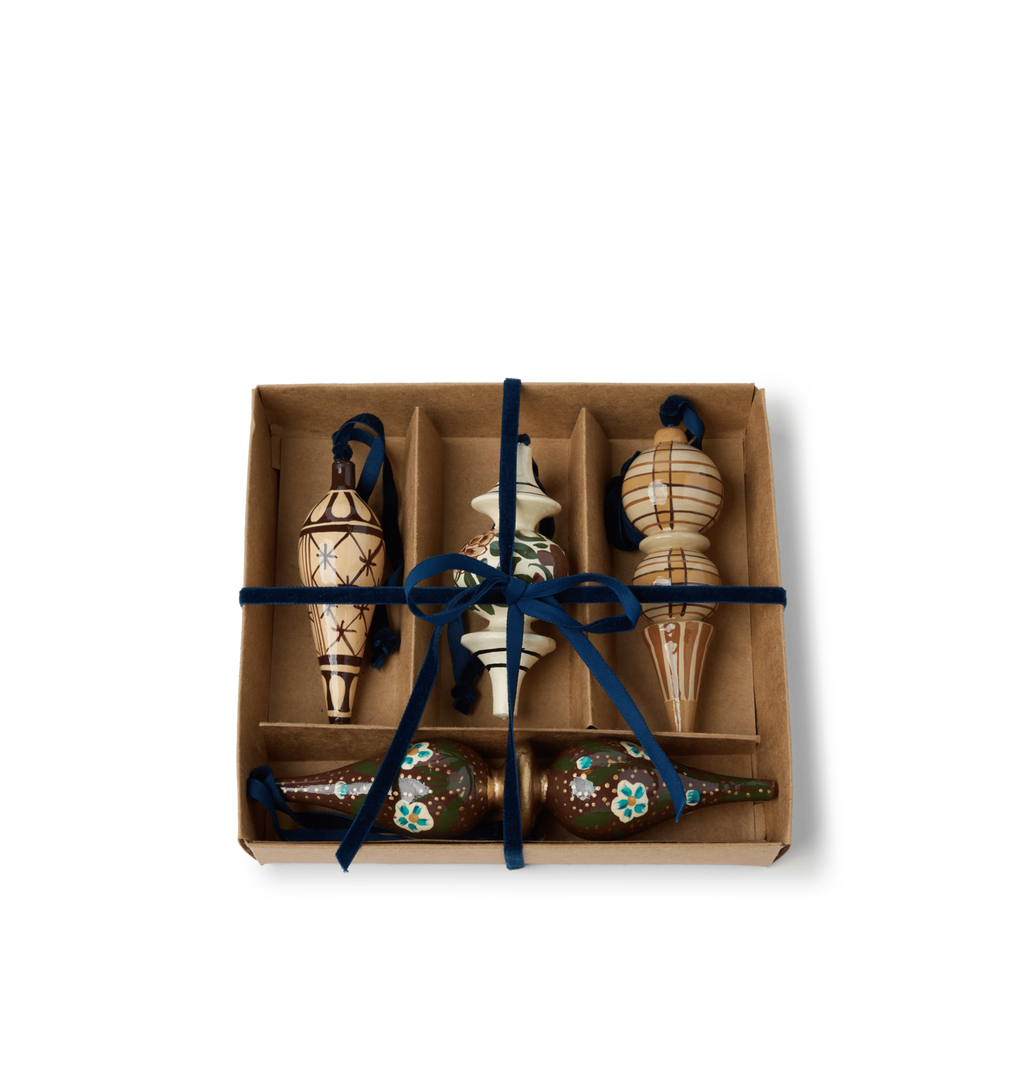A set of decorative wooden ornaments with star and floral patterns with blue velvet ties in a gift box