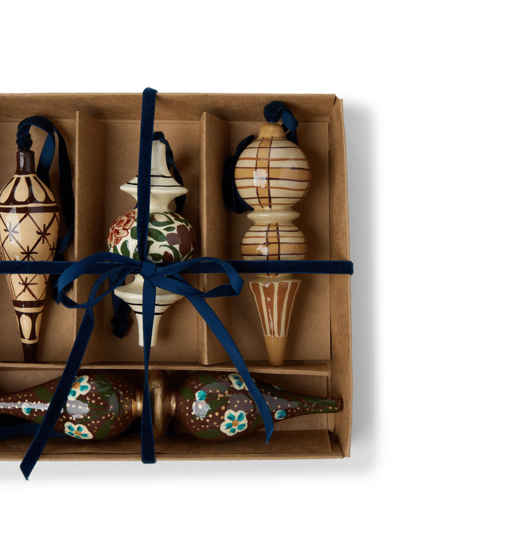 A set of decorative wooden ornaments with star and floral patterns with blue velvet ties in a gift box