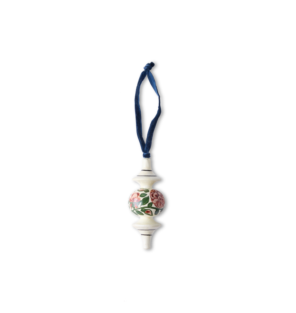 A hand-painted wooden ornament with traditional patterns and floral motifs with a velvet ribbon tie set on a white background
