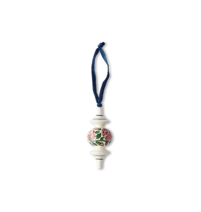 A hand-painted wooden ornament with traditional patterns and floral motifs with a velvet ribbon tie set on a white background