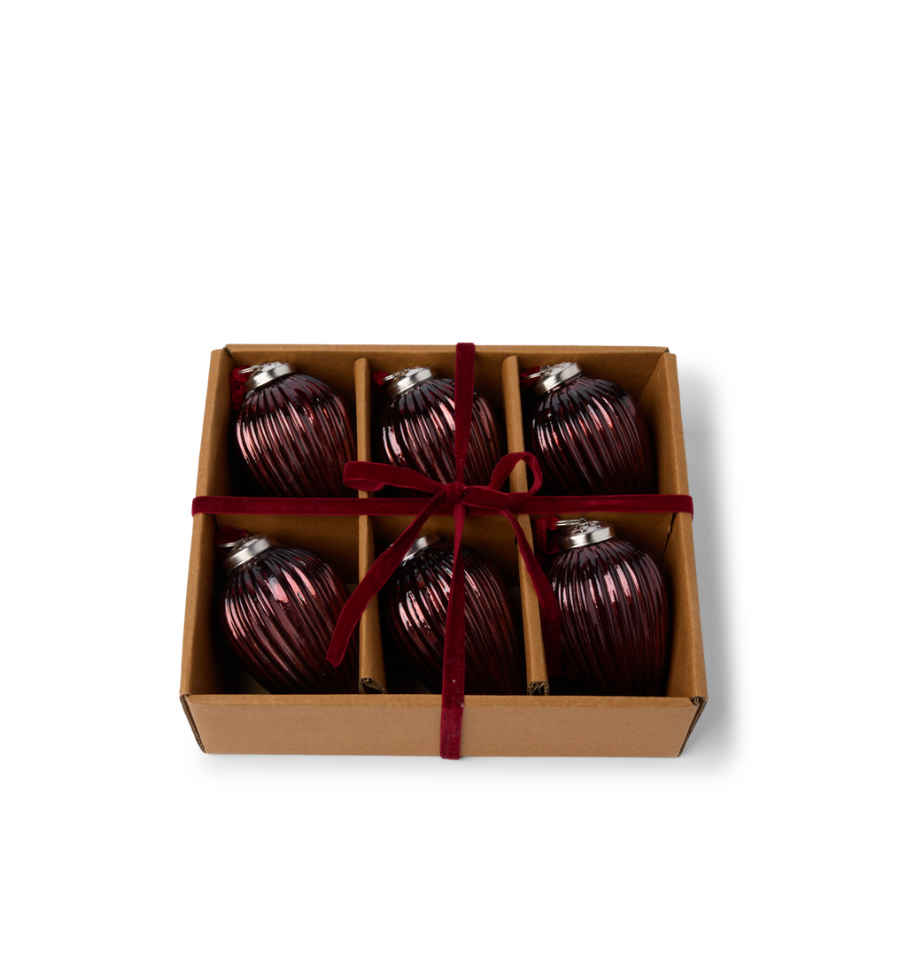 A gift set of brown glass ribbed ornaments in a cardboard box tied with a red velvet ribbon bow