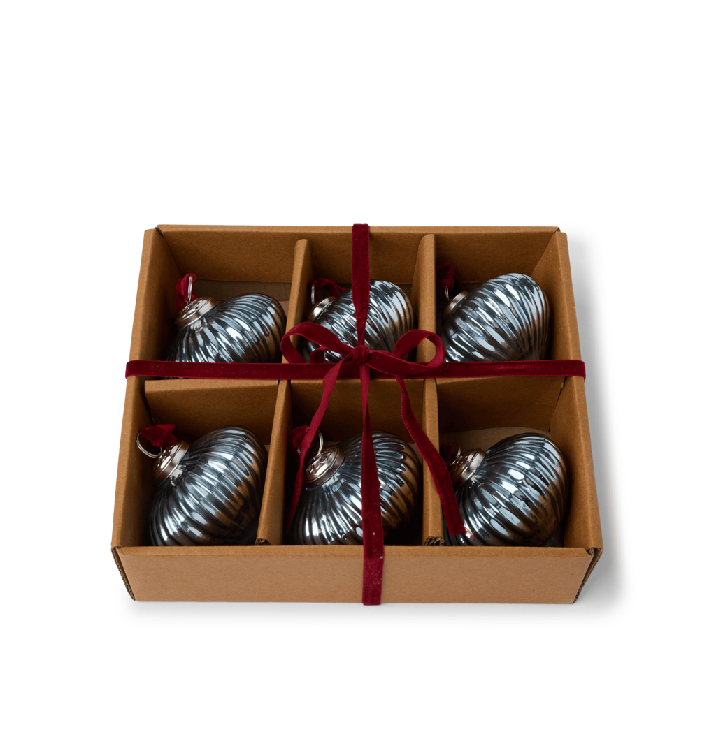 A gift set of light blue glass ribbed ornaments in a cardboard box tied with a red velvet ribbon bow