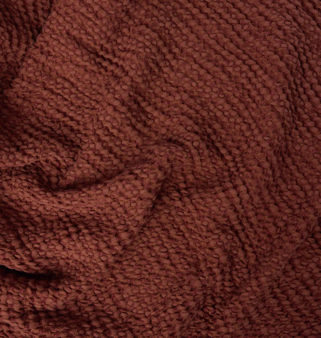 A detailed close up of a warm rust red waffle weave blanket 