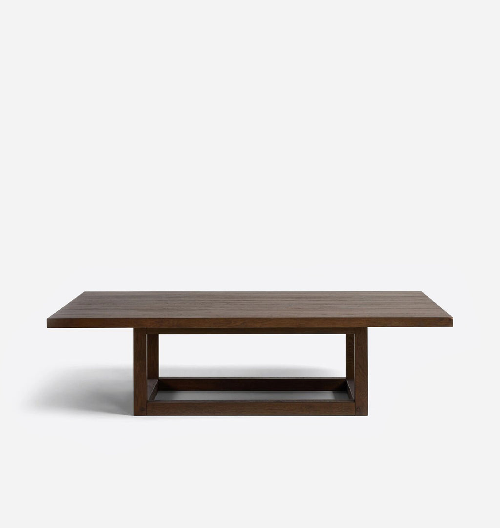 A rectangular dark brown wooden coffee table with a thick top and a geometric open-frame base, shown against a plain light gray background.