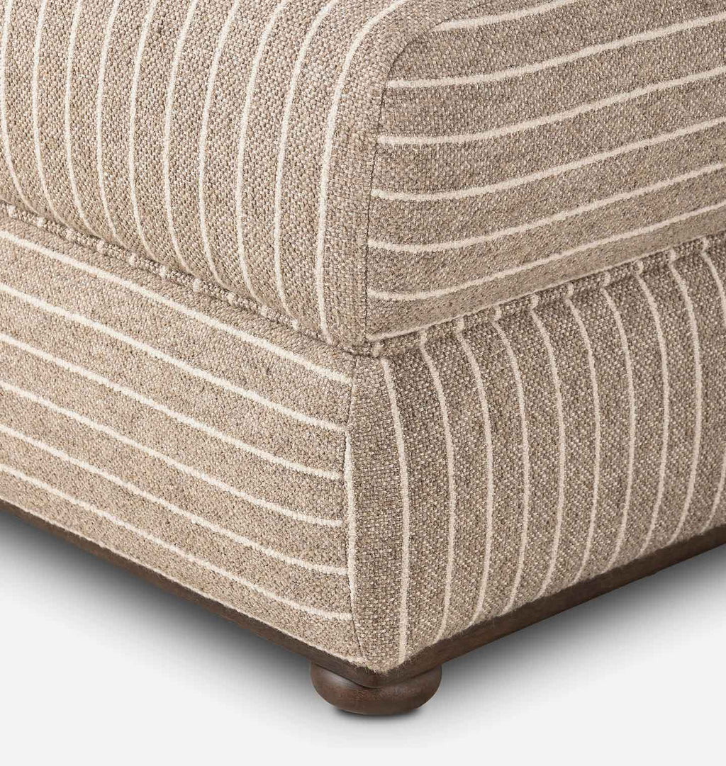 Close-up of upholstered furniture corner showing a woven fabric with vertical beige and white stripes, with a dark wood base and round feet visible.