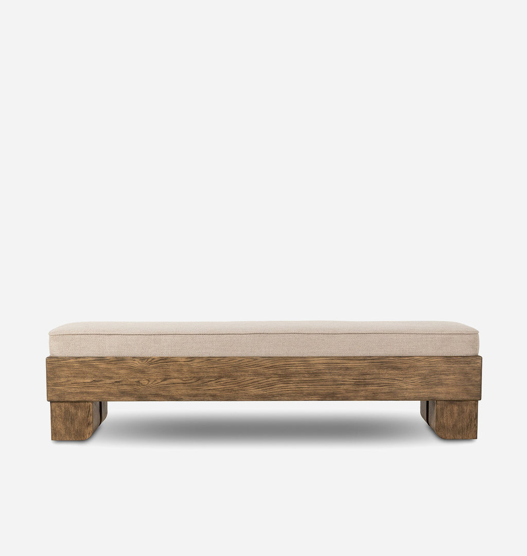 A rectangular upholstered bench with a thick beige fabric cushion and a rustic medium-brown wooden frame, shown against a plain light gray background.