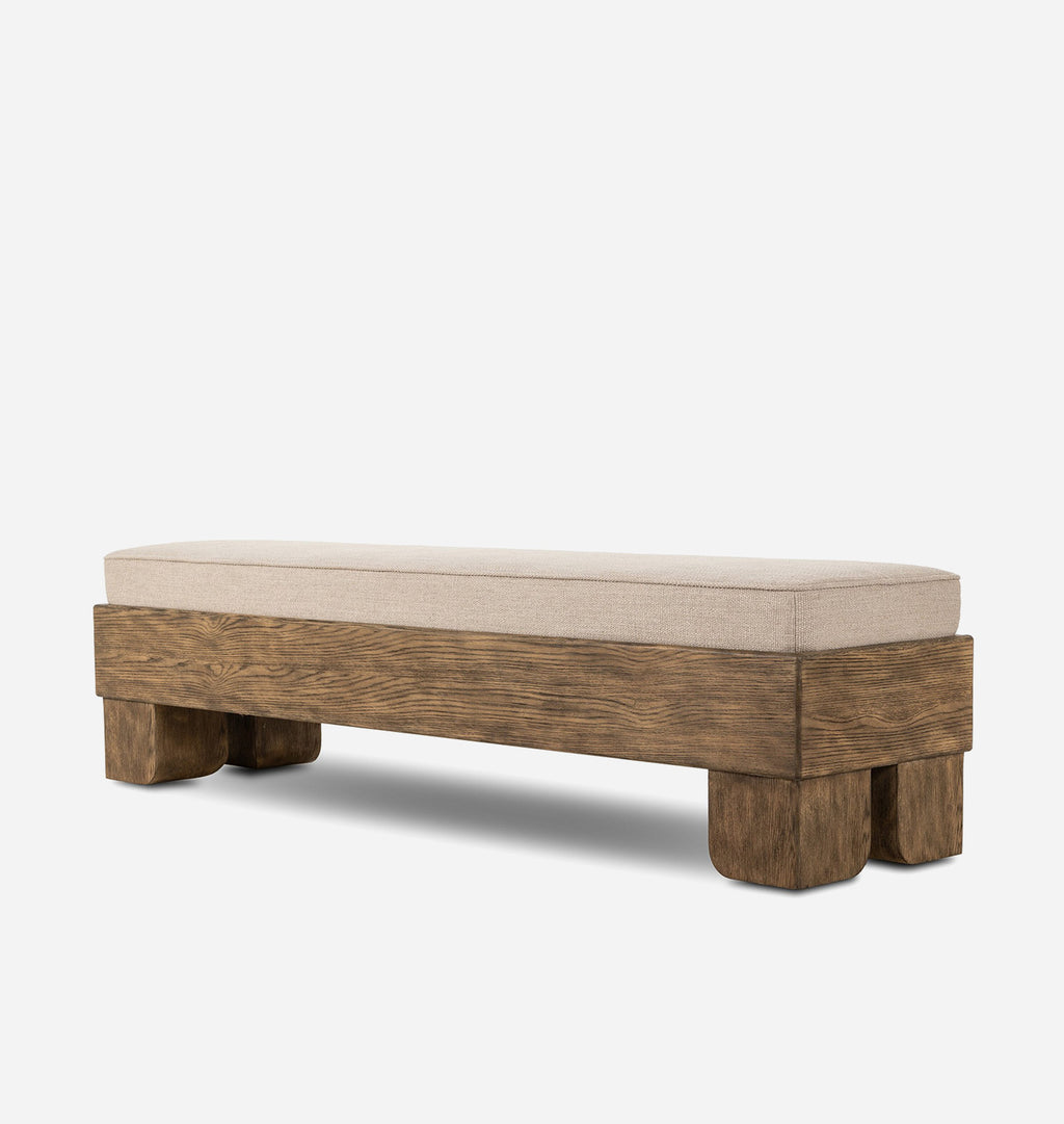 A rustic wooden bench with a thick upholstered seat cushion in a light beige fabric, shown against a plain light gray background.