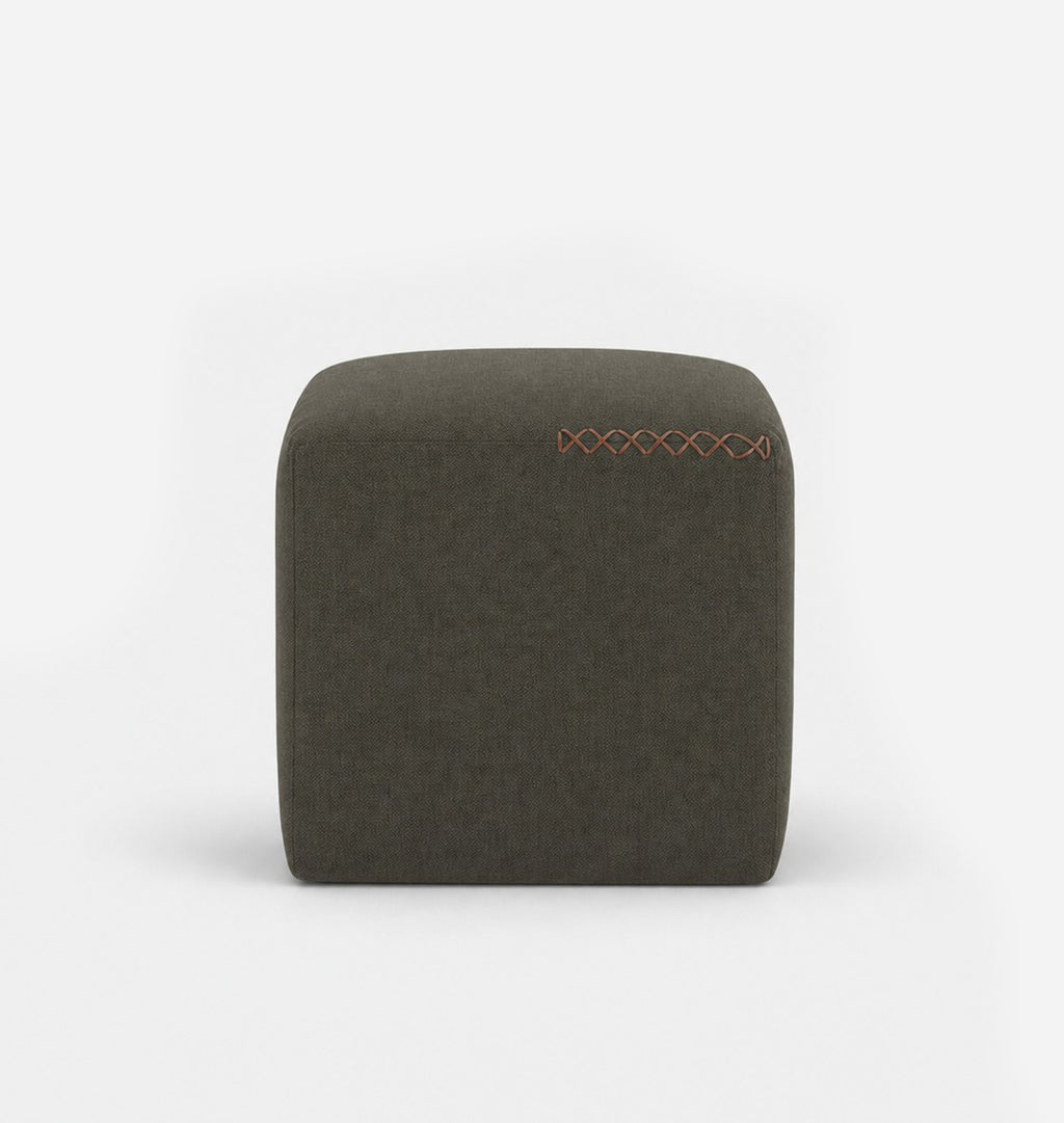 A square, low-profile pouf or ottoman upholstered in an olive textured fabric, featuring leather x-stitching on the top surface, set against a seamless white background.