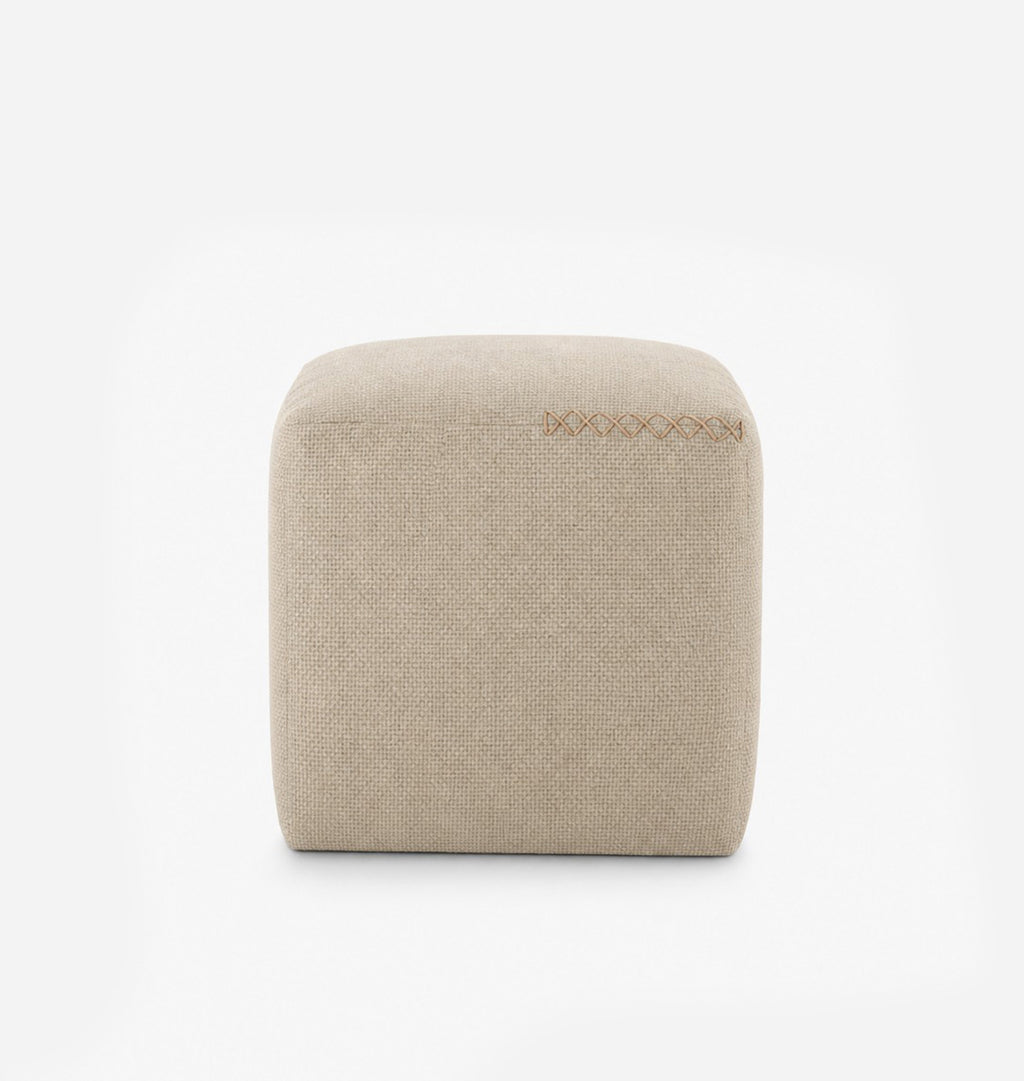 A square, low-profile pouf or ottoman upholstered in a light beige textured fabric, featuring leather x-stitching on the top surface, set against a seamless white background.