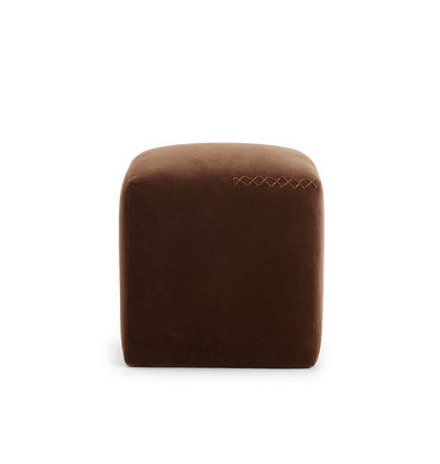 A square brown velvet ottoman with a leather x-stitched accent on the top edge, shown against a plain white background.