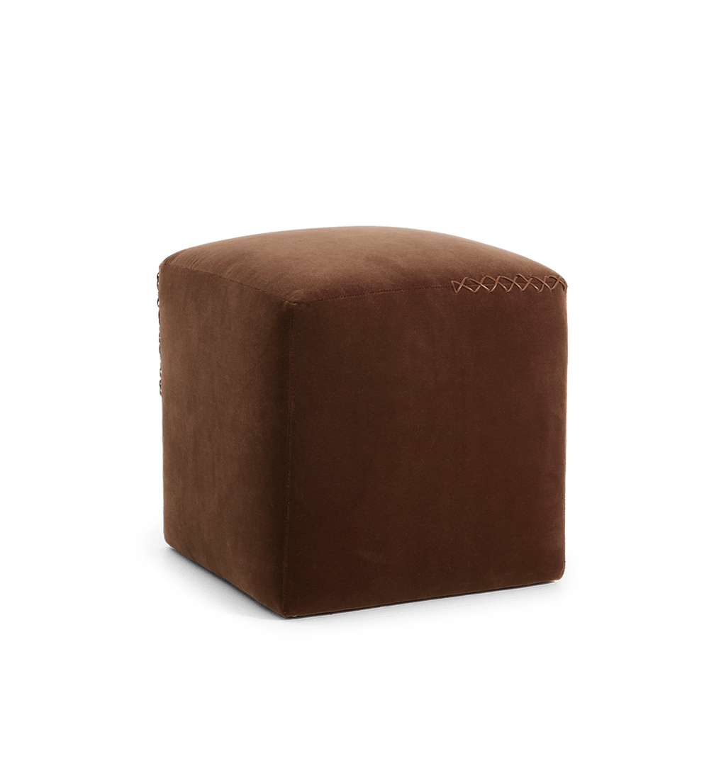A square brown velvet ottoman with a leather x-stitched accent on the top edge, shown in an angled view against a plain white background.