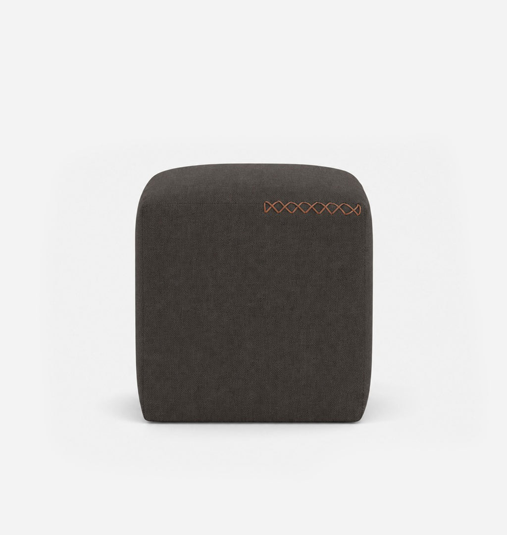 A square, low-profile pouf or ottoman upholstered in a dark muted brown textured fabric, featuring leather x-stitching on the top surface, set against a seamless white background.
