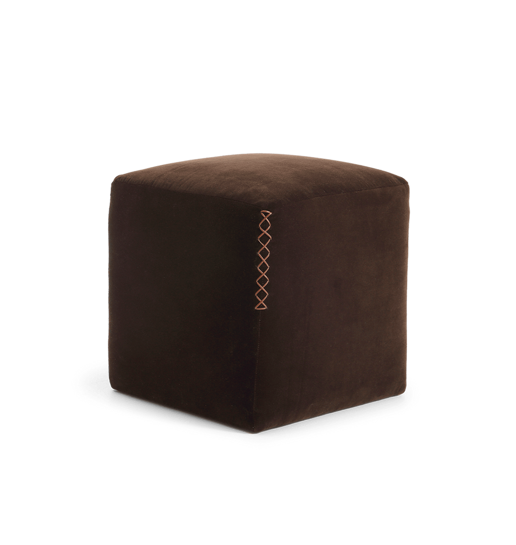 A square dark brown velvet ottoman with a leather x-stitched accent on the side edge, shown from an angled view against a plain white background.