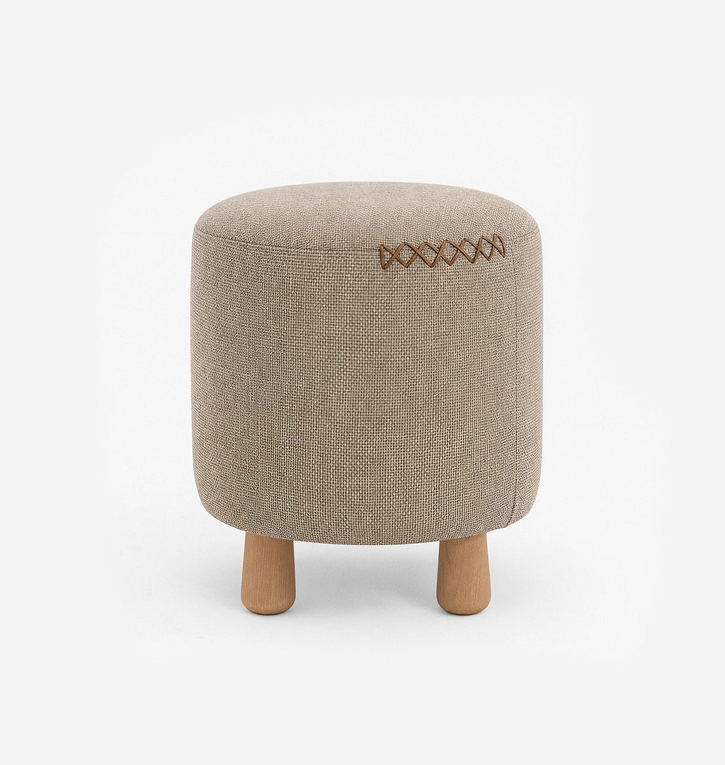 A round upholstered ottoman stool with a beige textured woven fabric with leather x-stitching and three short natural wood legs, shown against a plain white background.