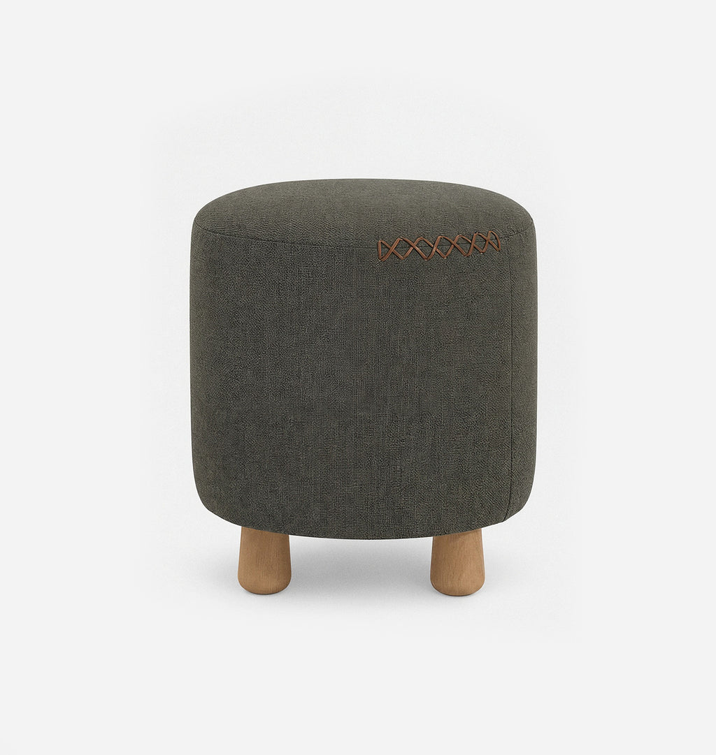 A round upholstered ottoman stool with a dark green textured linen fabric with leather x-stitching and three short natural wood legs, shown against a plain white background.