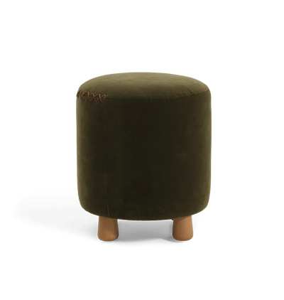 An olive green velvet cylindrical ottoman with short wooden legs and a decorative leather x-stitching on the top seam, shown against a plain white background.