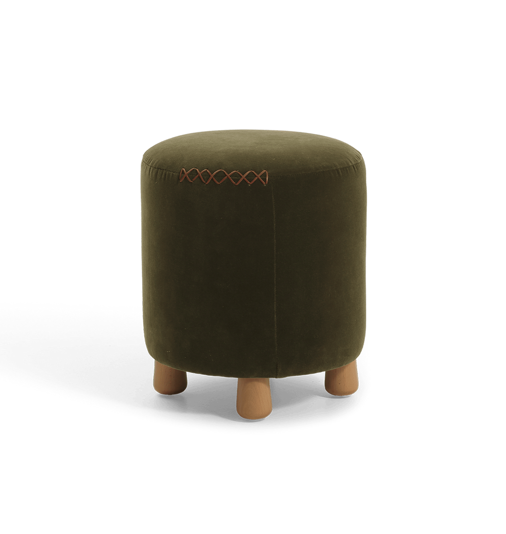 An olive green velvet cylindrical ottoman with short wooden legs and a decorative leather x-stitching on the top seam, shown against a plain white background.