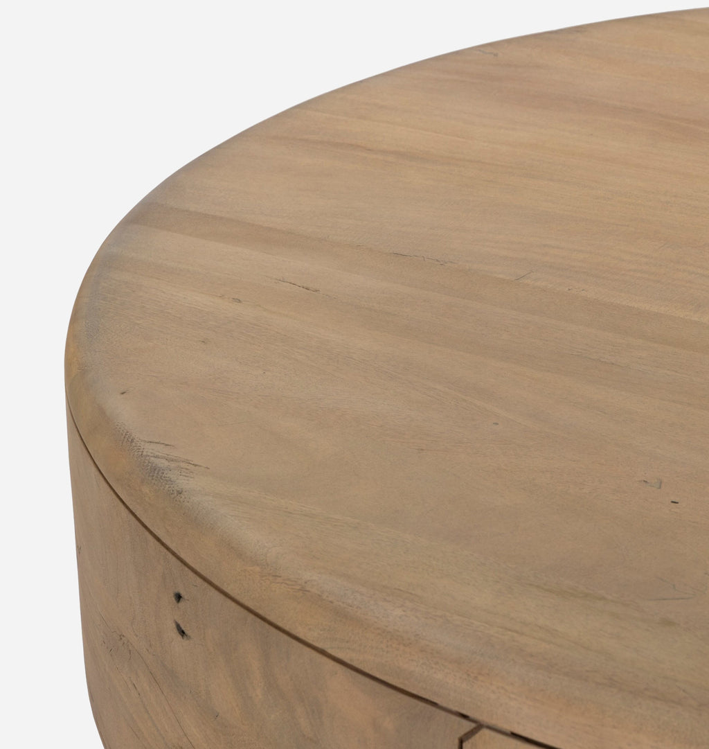 A close-up of a round, light oak wood coffee table on a white background