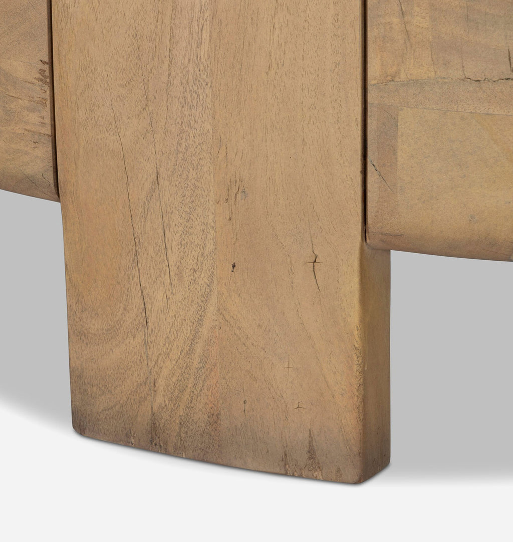 Close-up detail of a light brown wooden furniture piece, showing the grain and edge of a thick wooden leg or panel.