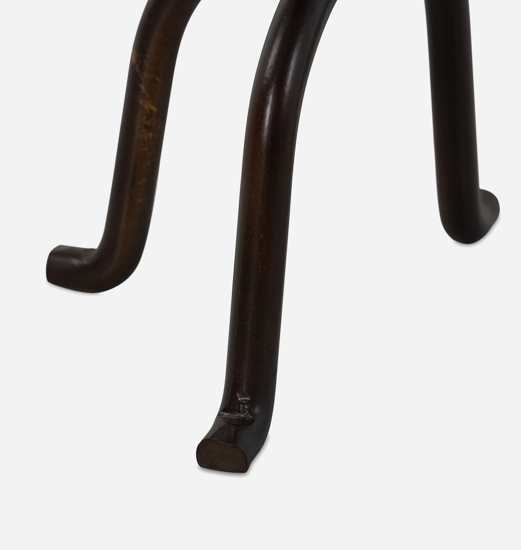 Close-up of a dark brown metal table leg with a curved back and straight front foot, shown against a light gray background.