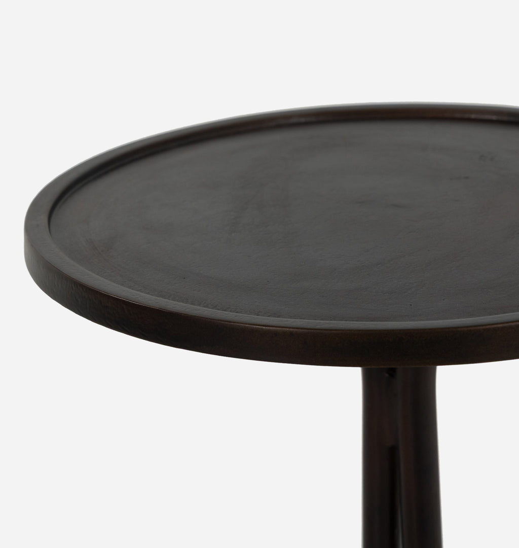 Close-up of a round dark brown metal side table showing the top surface and part of the leg against a light gray background.