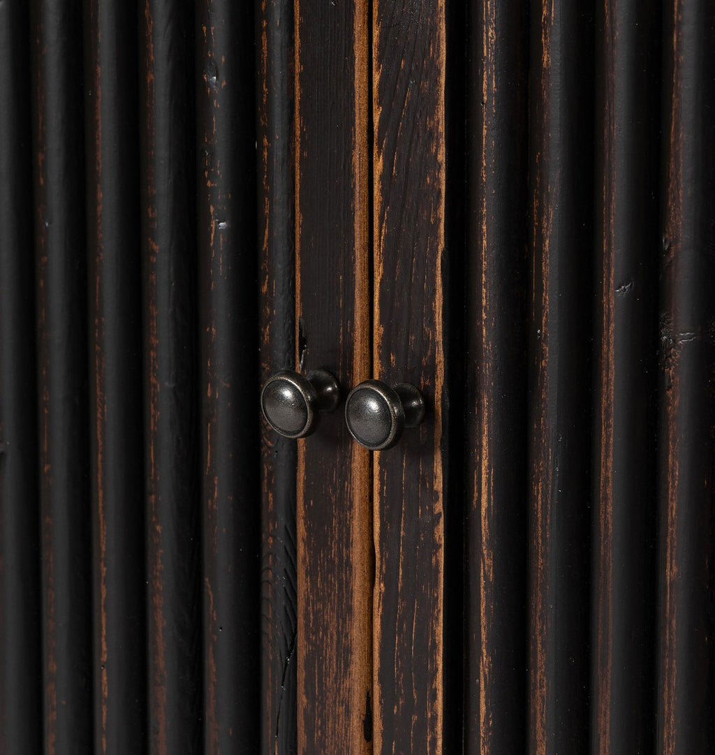 Close-up of dark distressed wood cabinet doors with vertical slats and two round dark metal knobs.