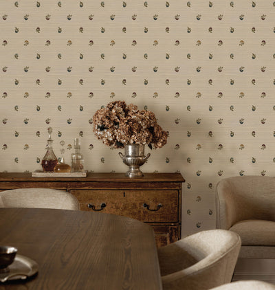 Beige Laila Multi Wallpaper with a repeating small floral pattern, shown in a styled dining room setting behind a wooden sideboard, vase of dried flowers, and upholstered chairs.