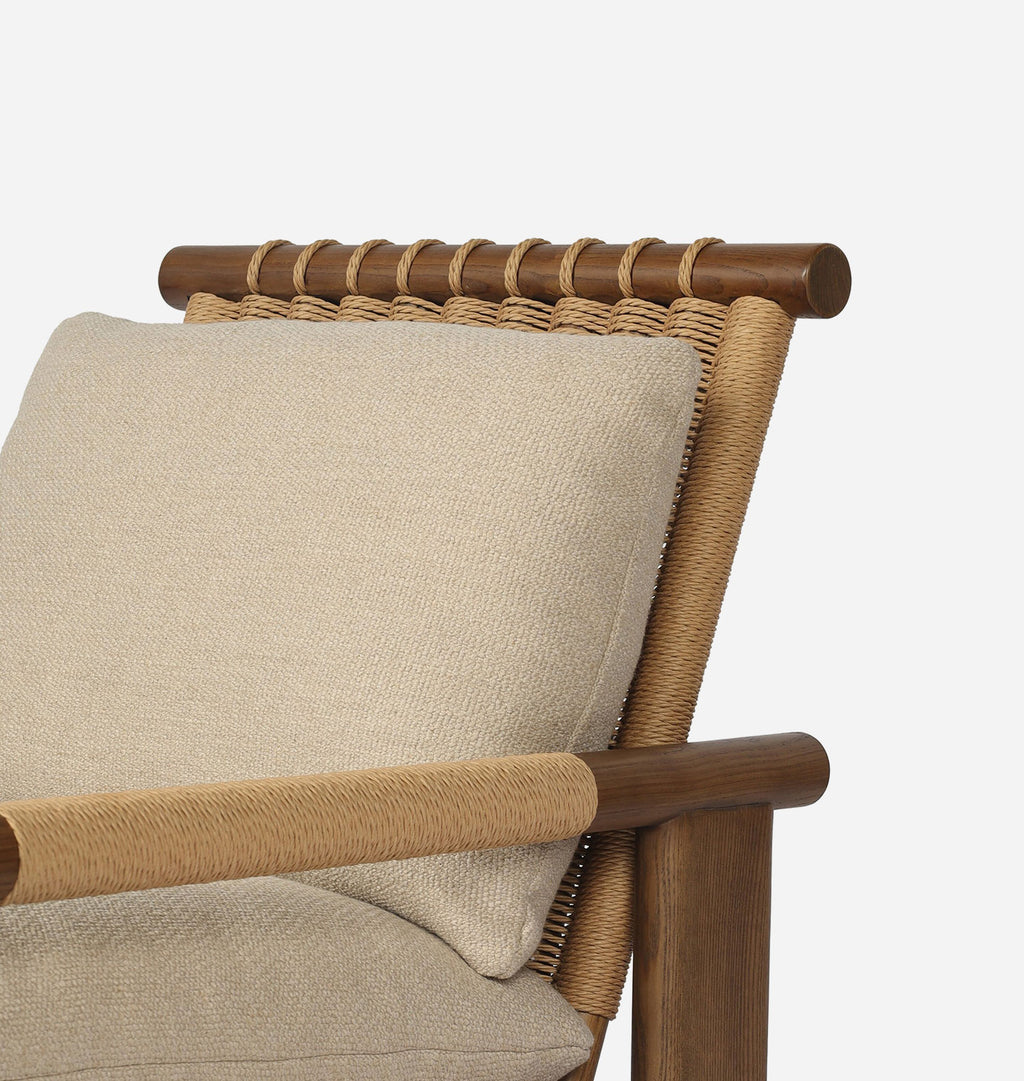Close-up of a wooden armchair with a beige woven seat cushion and a matching square throw pillow, showing the backrest, armrest, and rope-wrapped details against a light gray background.