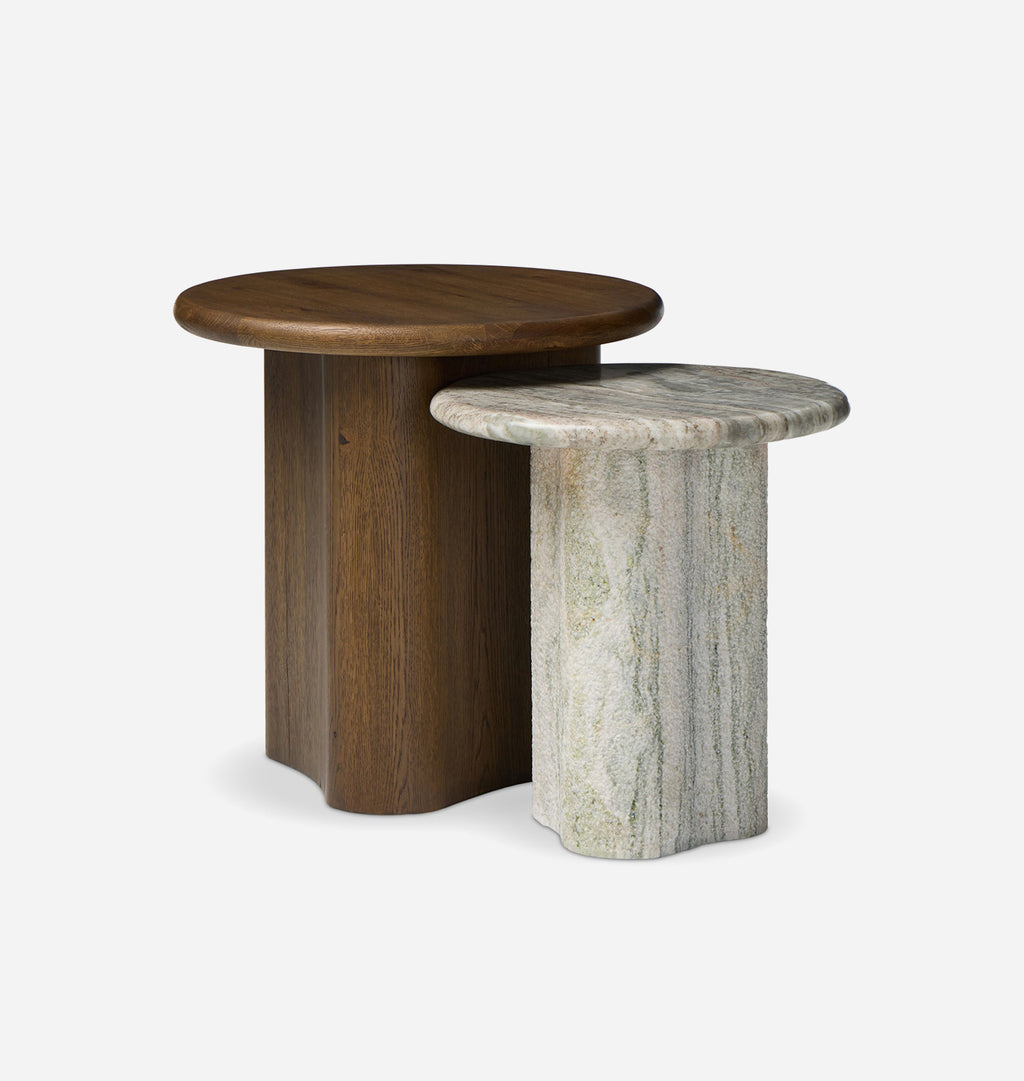Two nesting side tables on a light gray background: one with a dark brown wooden base and round top, and one with a light gray and white veined stone base and round top.