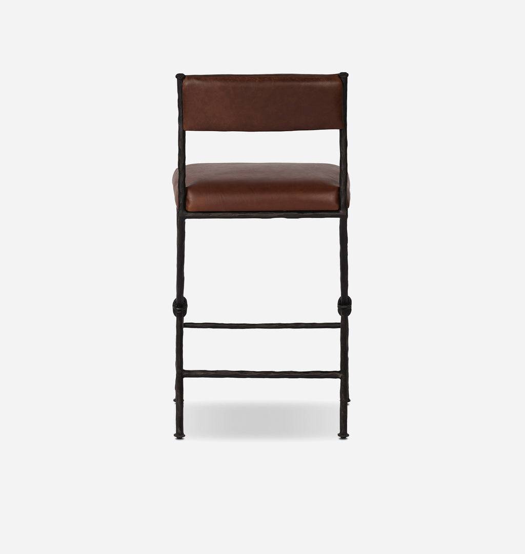 A mid-century modern bar stool with a brown leather cushioned seat and backrest, supported by a black metal frame with decorative ball accents on the legs.