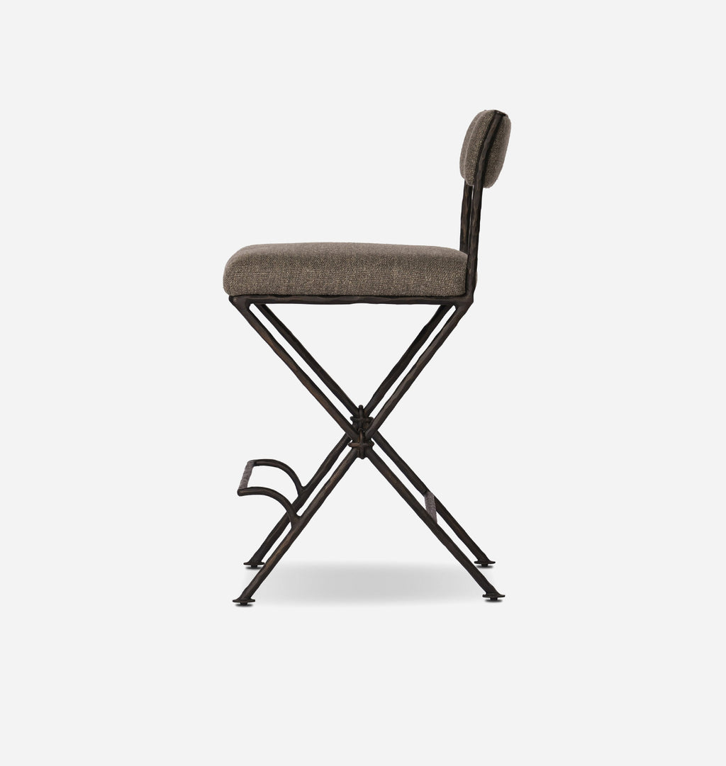 A modern folding bar stool with a textured taupe upholstered seat and backrest, supported by a black metal X-frame base with a footrest.