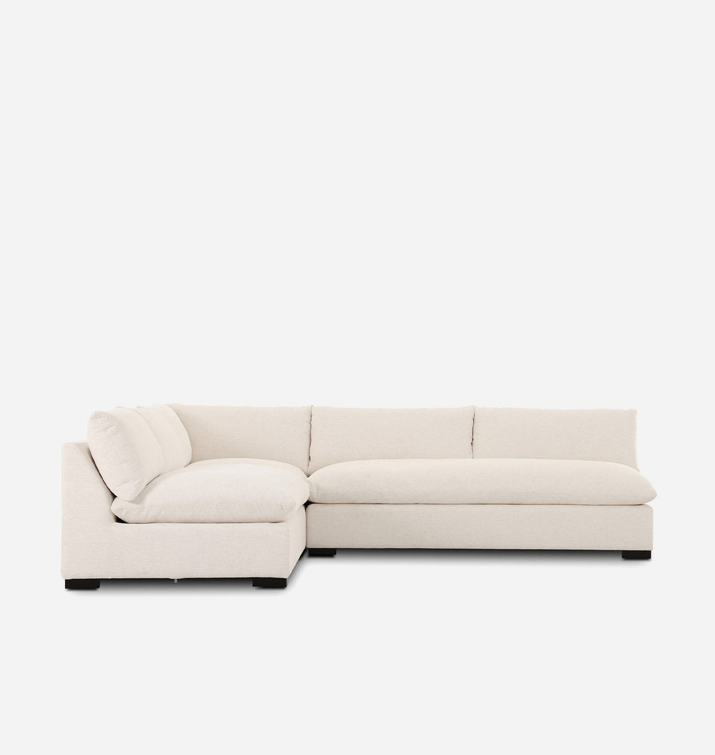 A modern sectional sofa upholstered in a light cream fabric, featuring a lchaise lounge and a low rectangular seat, shown against a plain white background.
