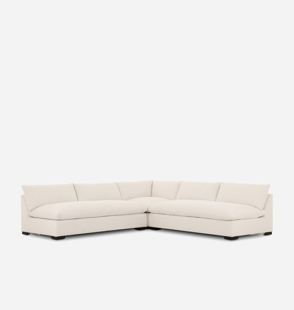 A modern sectional sofa upholstered in a light cream fabric, featuring a chaise lounge and a low rectangular seat, shown against a plain white background.