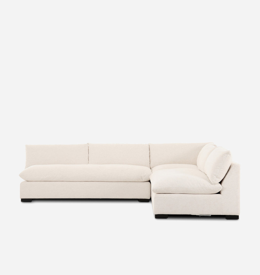 A modern sectional sofa upholstered in a light cream fabric, featuring a chaise lounge and a low rectangular seat, shown against a plain white background.