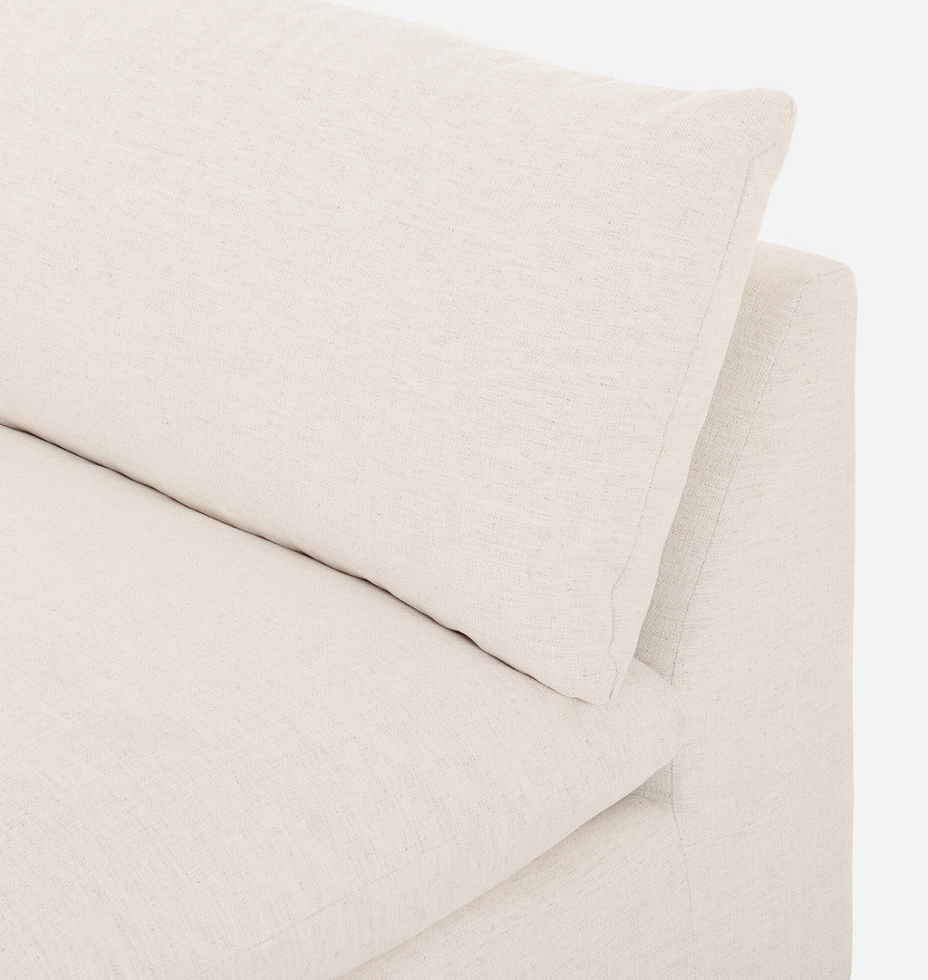 Close-up of a light beige upholstered sofa corner with a matching back cushion, showing the fabric texture and clean lines against a white background.