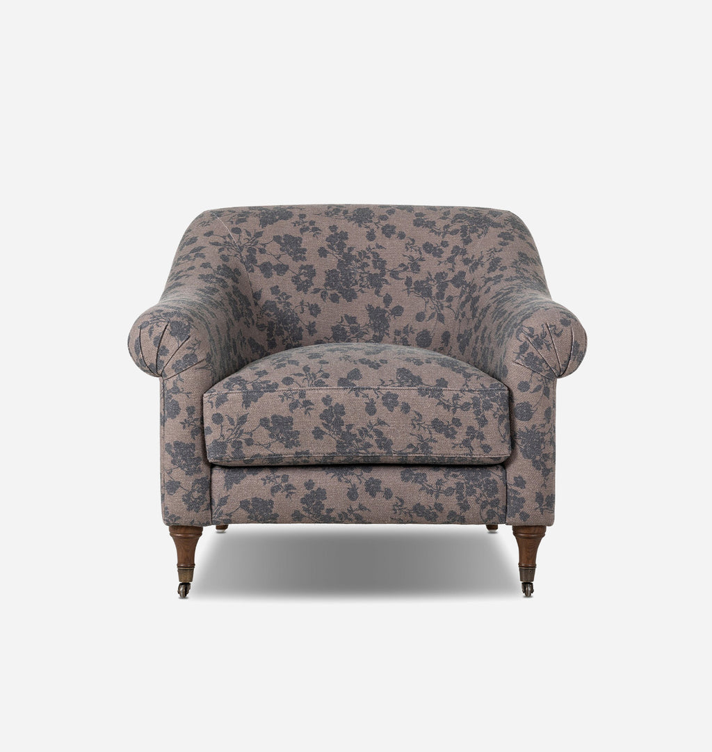 A vintage-style upholstered armchair with a dusty pink floral pattern and dark brown wooden legs, shown from a front angle against a light gray background.
